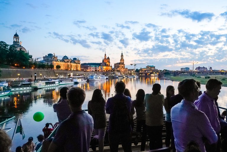 Menschen stehen auf der Wissenschaftsfahrt und betrachten die abendliche Elbe / Englisch:People stand on the science ride and look at the Elbe in the evening