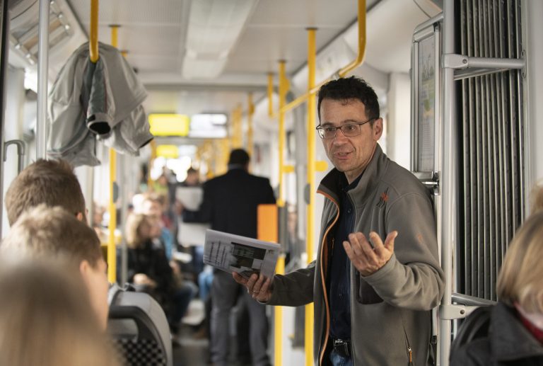 Mann steht im Tram und spricht mit jemandem / Englisch:Man standing in streetcar talking to someone