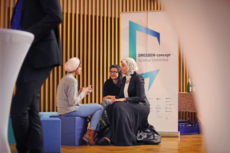 Menschen sitzen auf den Sitzwürfel von DRESDEN-concept und unterhalten sich / Englisch:People sit on the seating cubes of DRESDEN-concept and talk to each other