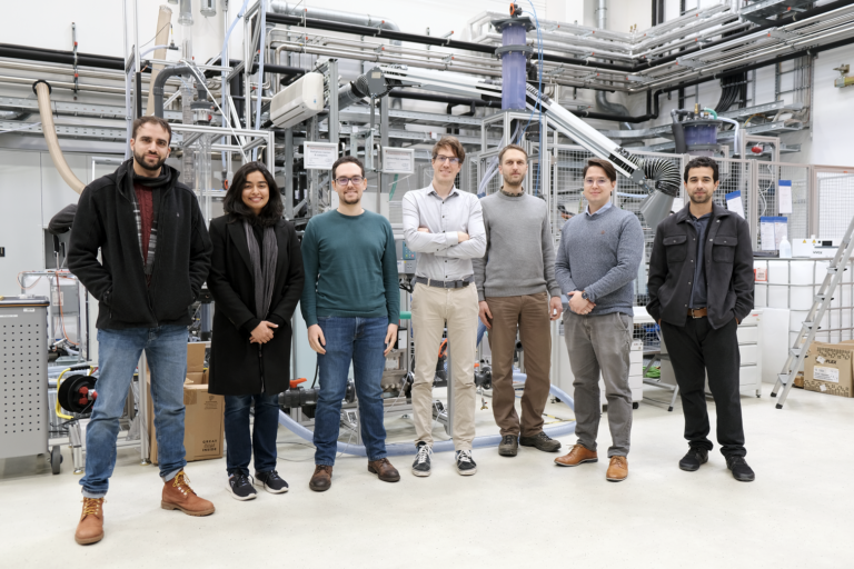 Ein Gruppenfoto von 7 Personen, im Hintergrund sind Großgeräte zu sehen.