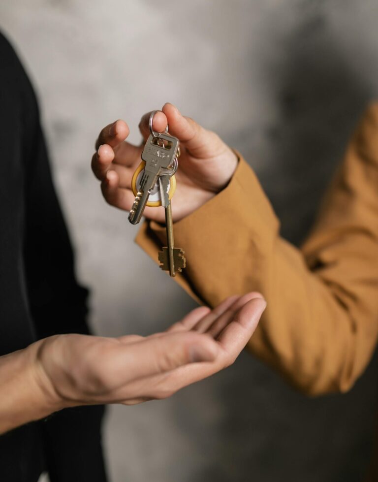 One person is handing over a set of keys to another person. Logo