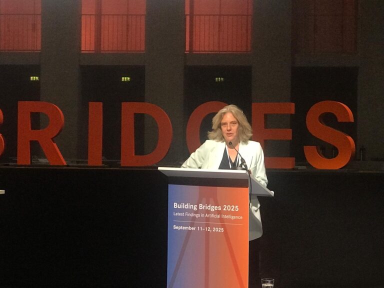 Eine Person steht hinter einem Rednerpult mit der Aufschrift Building Bridges 2025, Latest Findings in Artificial Intelligence, September 11 to 12, 2025 Logo