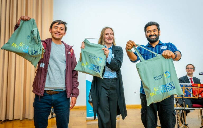 3 people are happily holding bags with the logo DRESDEN-concept and the inscription Science and Innovation Logo